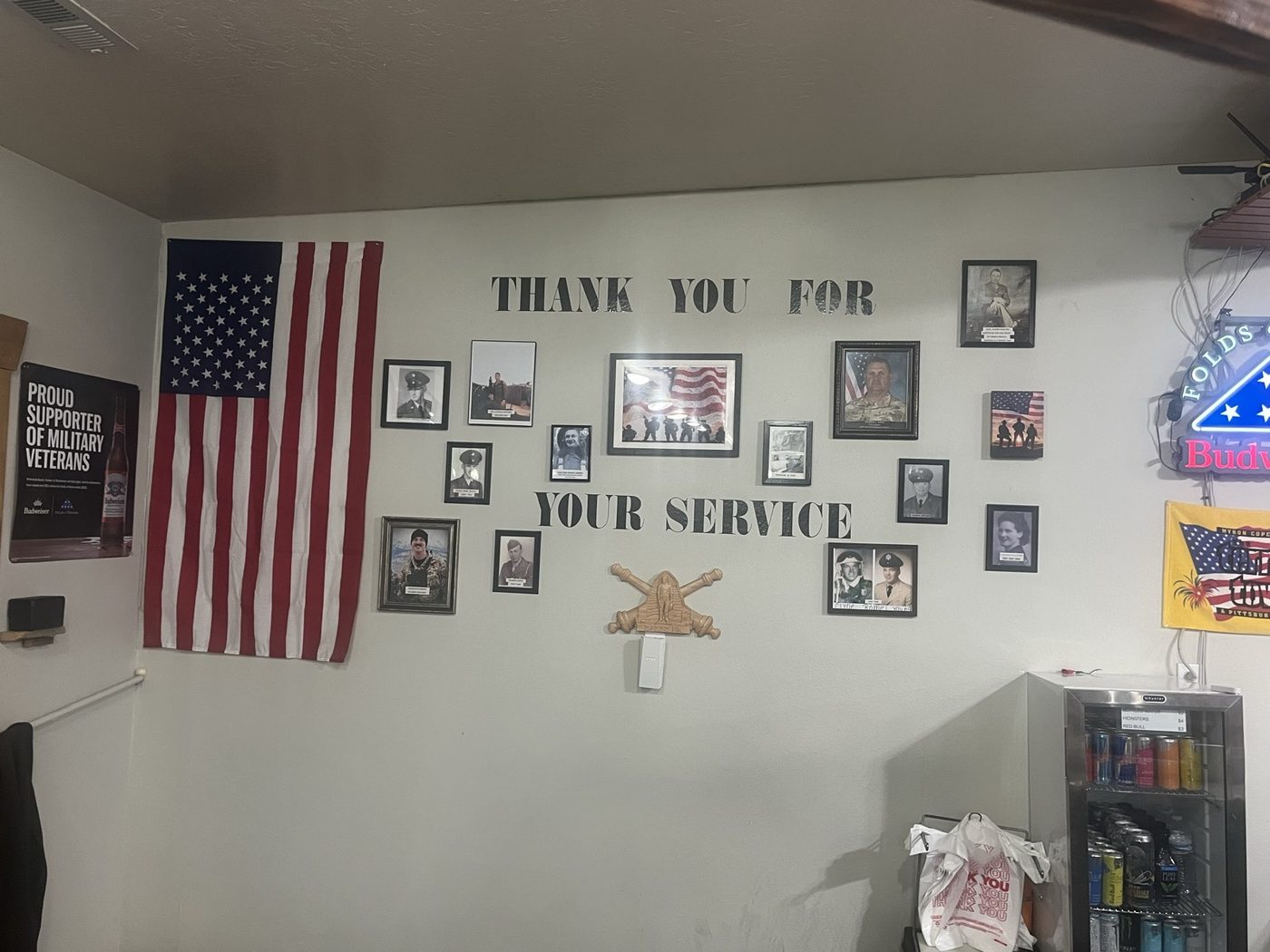 The Thank You For Your Service wall at Giff's, hung with photographs and a US flag